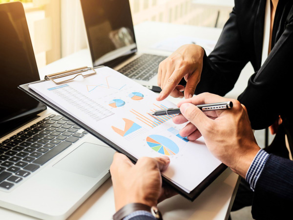 Hand holding a clipboard, pointing at graphs